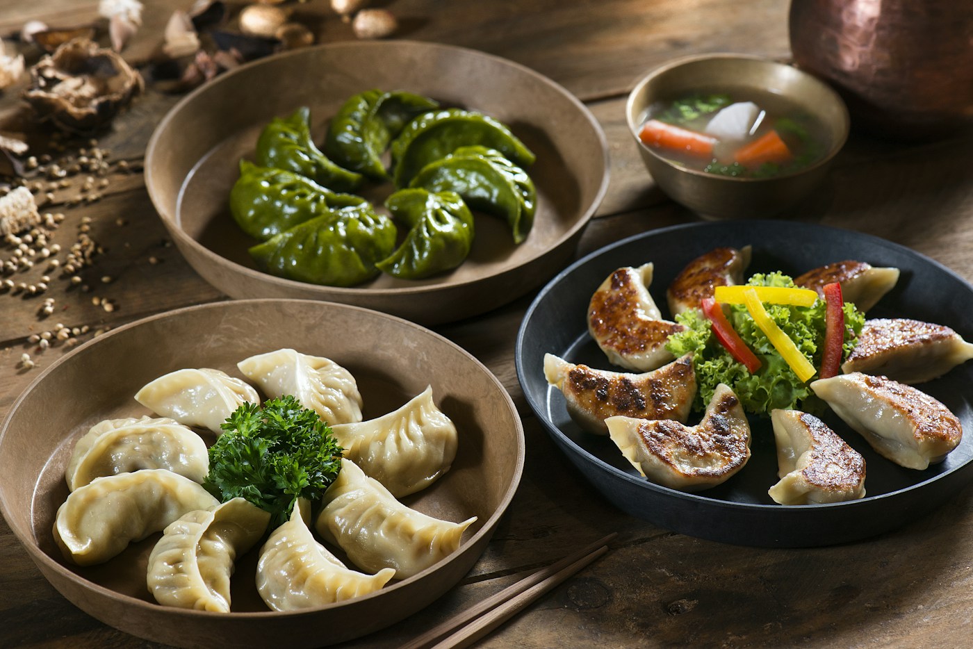 Plates of handmade steamed and pan-fried dumplings on a wooden table